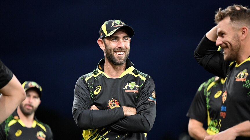 一个留着胡子的男人澳大利亚 T20 板球制服微笑着交叉双臂。
